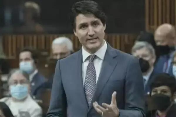 Justin Trudeau talking wearing a dark blue-gray suit with a black and white patterned tie