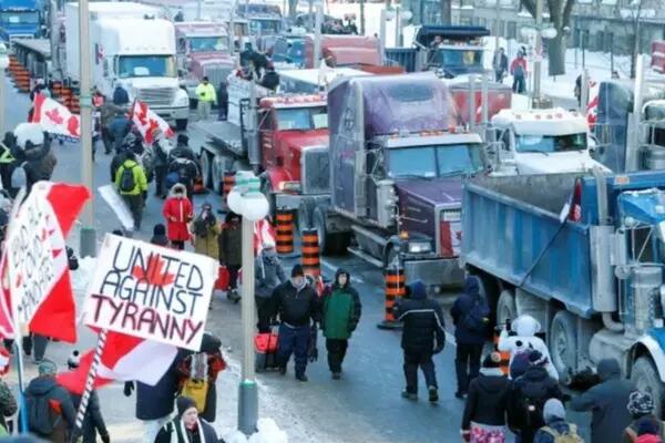 Trucker convoy, hoards of trucks and people, with a sign that says "United Against Tyranny"