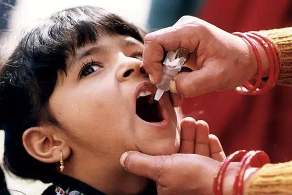 A young child receives a dose of polio medicine in India