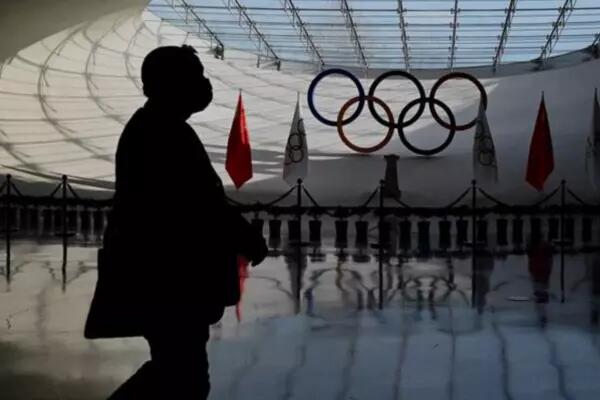A silhouette walks by the Olympic rings in a facility in Beijing, China