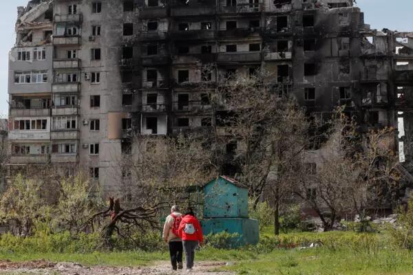 Two people stand outside of a bombed out building in Mariupol, Ukraine