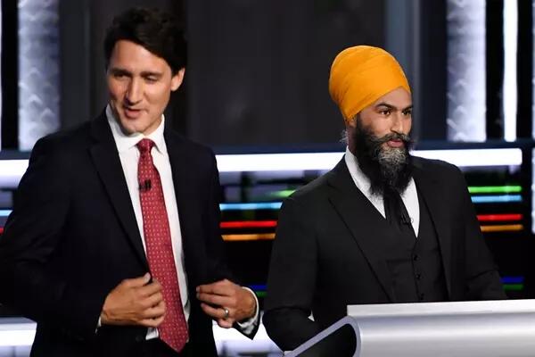 Prime Minister Justin Trudeau, left, wears a black suit and red tie. On the right, NDP Leader Jagmeet Singh wears a black suit and tie with a orange-yellow turban.