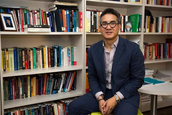Joseph Wong sits in front of a bookshelf.