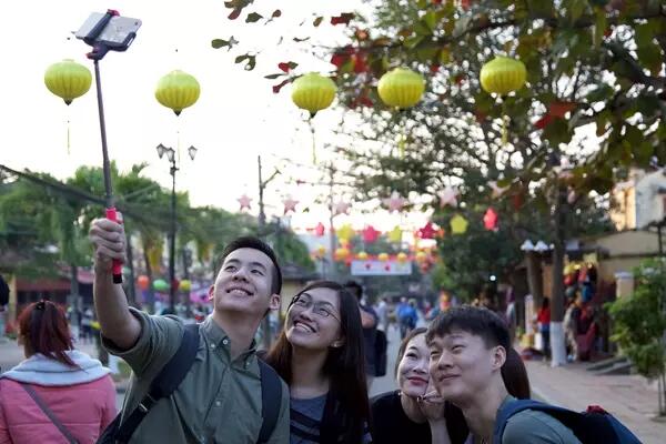Photo of students taking a selfie in Vietnam street, with a string of yellow lanterns above