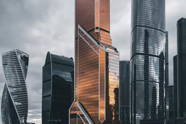 A copper coloured tower in Moscow is illuminated against other tall grey buildings.