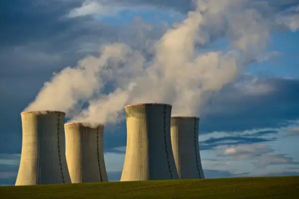 Four nuclear stacks with smoke blowing into a blue sky