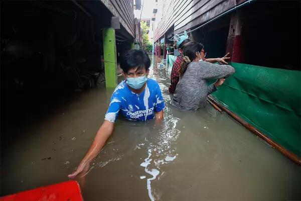 A Thai man navigates near chest deep water in a flooded street