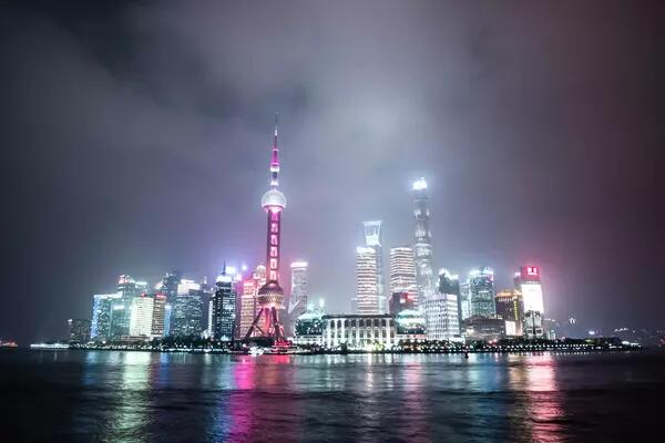 A futuristic Shanghai skyline is lit up in neon green and white against a dark sky and sea.