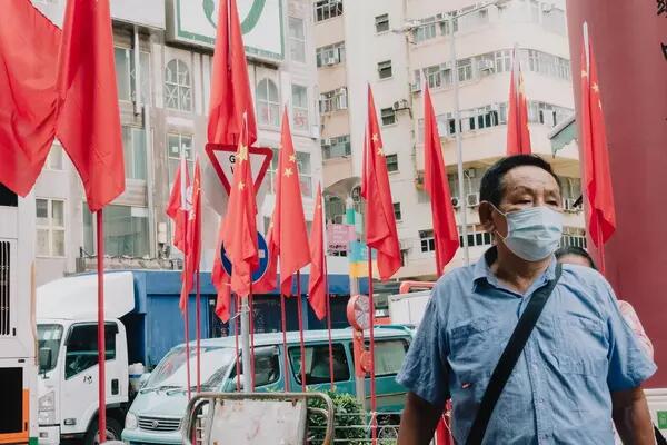 Masked man walks on the street amongst Chinese flags