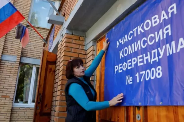 A member of the local electoral commission in Donetsk, Ukraine, hangs a banner on the doors of a polling station on Thursday, ahead of a planned referendum on joining Russia. The banner reads: 'District сommission of referendum no. 17008.' (Alexander Ermochenko/Reuters)