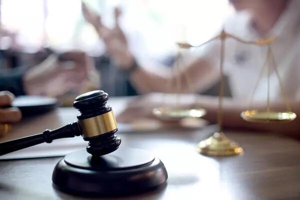 A Gavel rests on the table with scales in the background