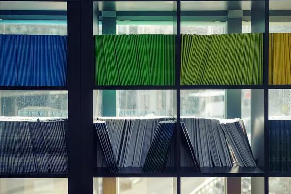 Multicoloured journals on shelves facing a window