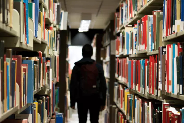 A person walks between two full shelves of books