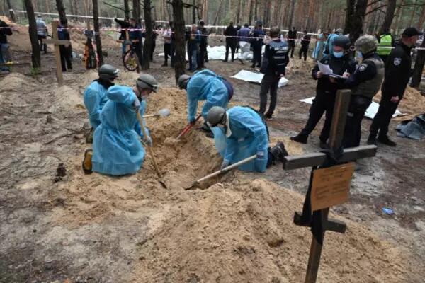 Forensic technicians dig a grave in a forest on the outskirts of Izyum, eastern Ukraine on September 16, 2022 [File: AFP/Sergey Bobok]