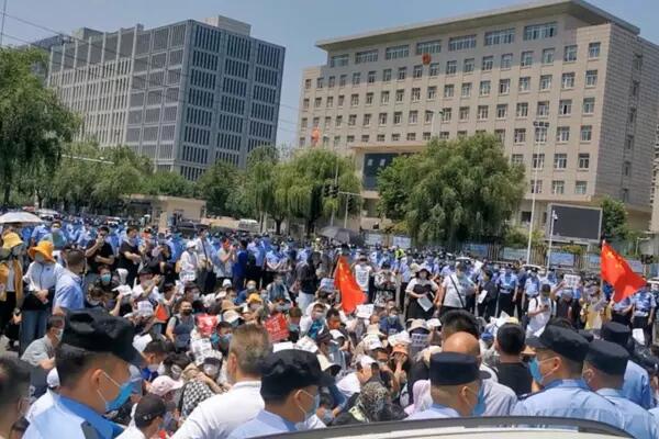 Police officers stand near demonstrators taking part in a protest over the freezing of deposits by some rural-based banks, in Zhengzhou, Henan province, China May 23, 2022, in this screengrab taken from a video obtained by Reuters.
