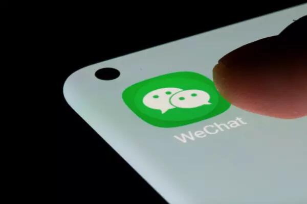 WeChat icon on a phone screen, as a finger goes to tap the app