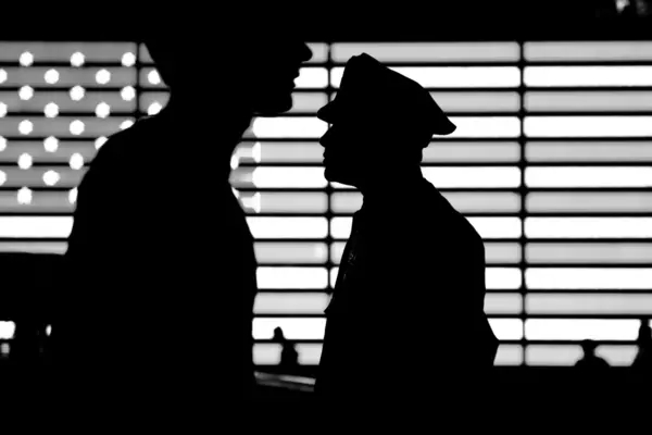 Silhouettes of two police officers in black and white, against the US flag