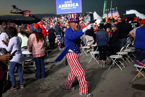 A man at a Trump Rally is dressed as Uncle Sam, a "Save America" sign is in the background