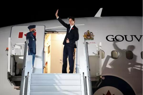 Justin Trudeau waves as he exits a plane