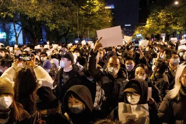People hold white sheets of paper in protest of coronavirus disease (COVID-19) restrictions, after a vigil for the victims of a fire in Urumqi, as outbreaks of the coronavirus disease continue in Beijing, China,