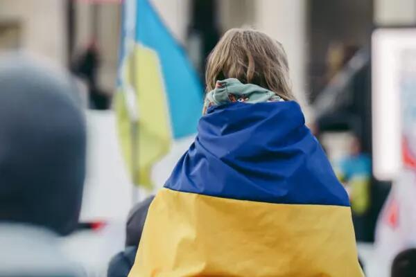 Image of a child with a Ukrainian flag wrapped around her shoulders