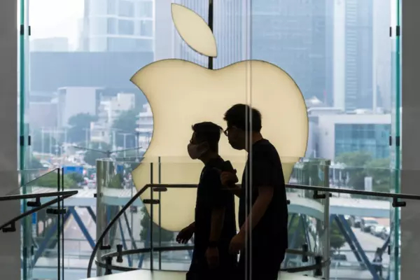 An Apple worker is seen in front of the Apple company logo in Hong Kong, on Sept, 16, 2022. 