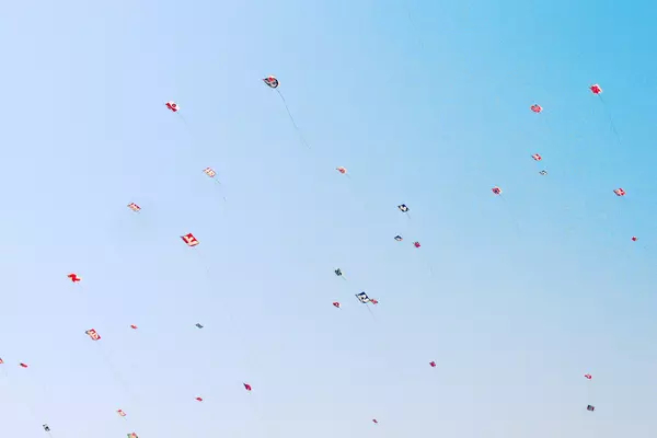 Dozens of brightly coloured kits float high in the blue sky