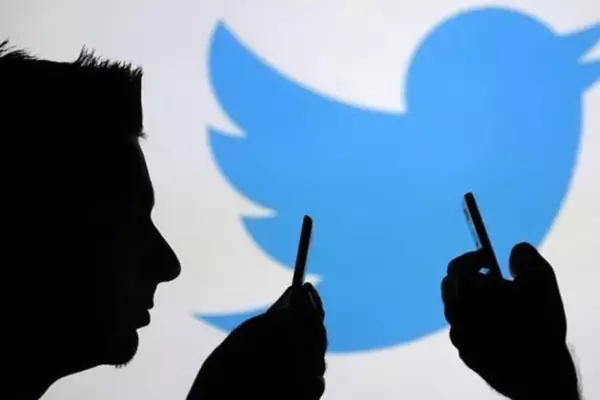 Two twitter users hold their phones with the Twitter logo in the background