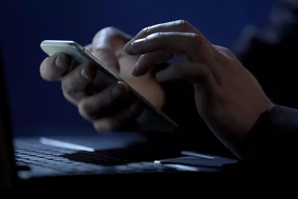 A pair of hands typing on a smartphone
