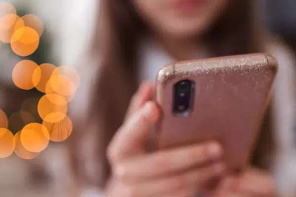 Close up of a girl holding a sparkly, pink phone