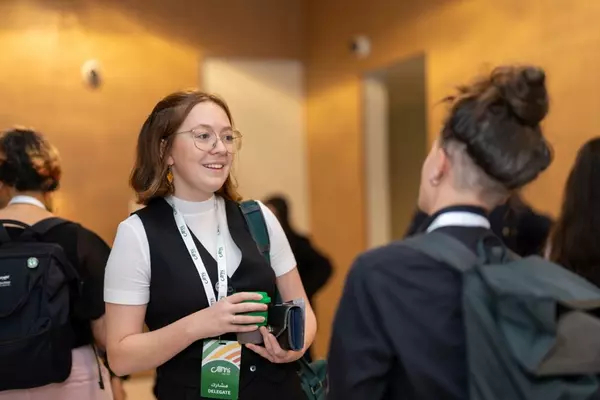 Amalie Wilkinson, Munk One alumnus, speaks to a colleague at COP28 in December, 2023. Amalie is pictured wearing an official COP28 lanyard.