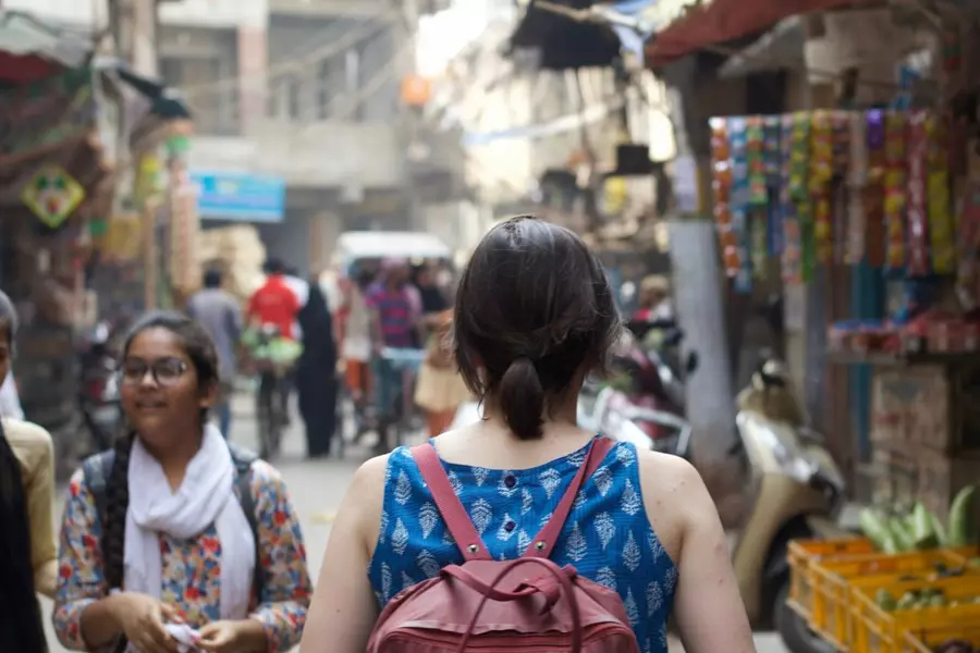 Student with backpack on stares out at a busy street market in India