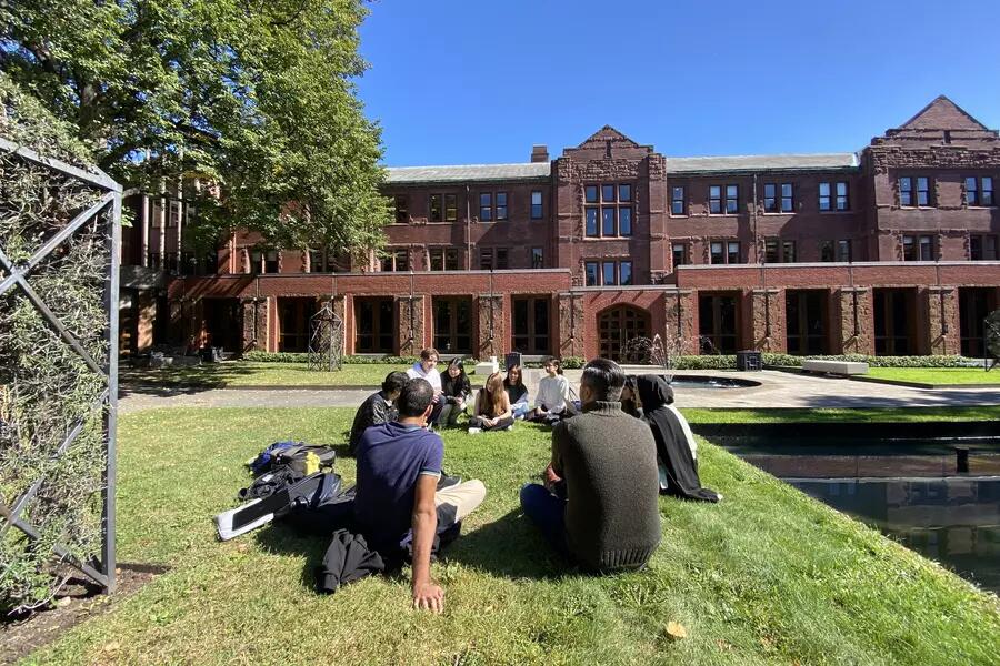 Students and Munk One Director Don Kingsbury sit on the lawn in front of the Munk School building at 1 Devonshire Place