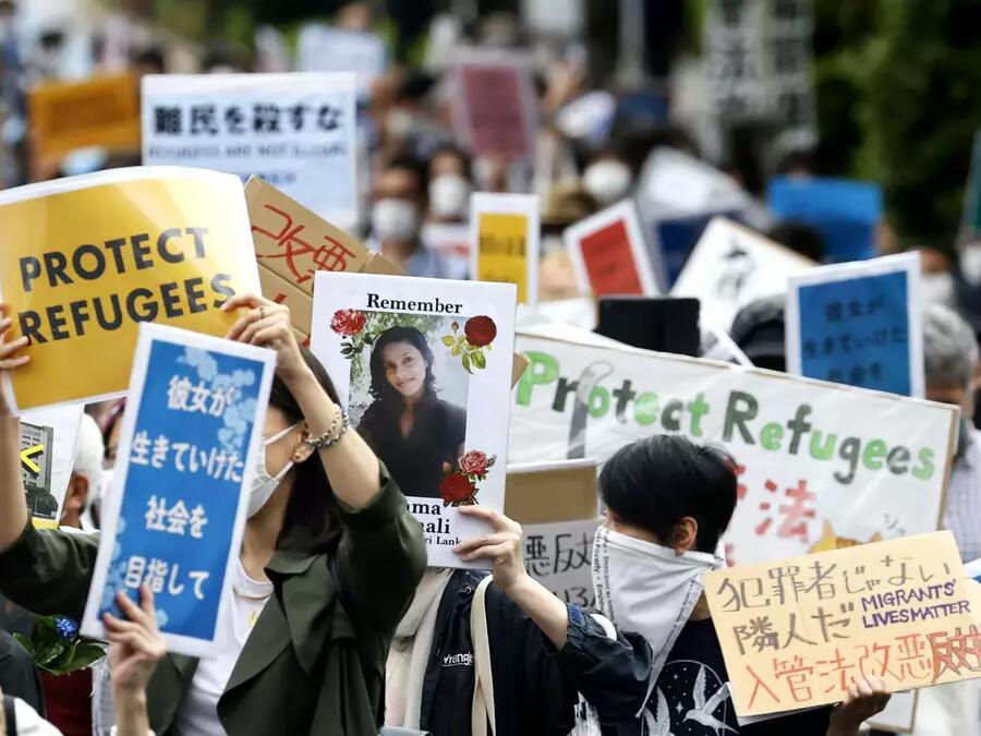 Crowd of people holding up banners in Japanese and English