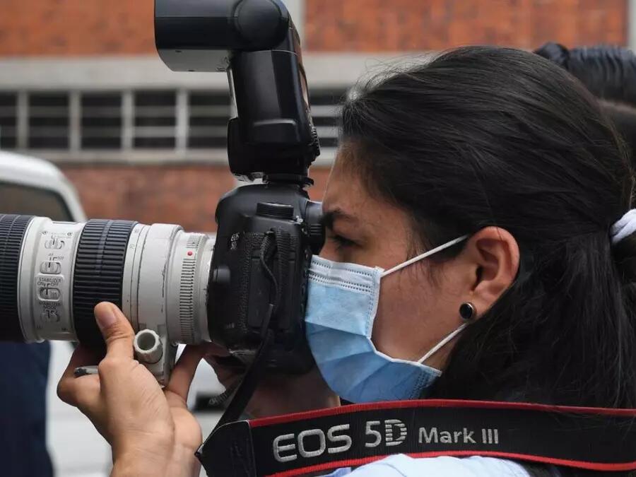 A photojournalist wears a surgical mask during a press conference in San Salvador on April 21, 2020. YURI CORTEZ/AFP via Getty Images  