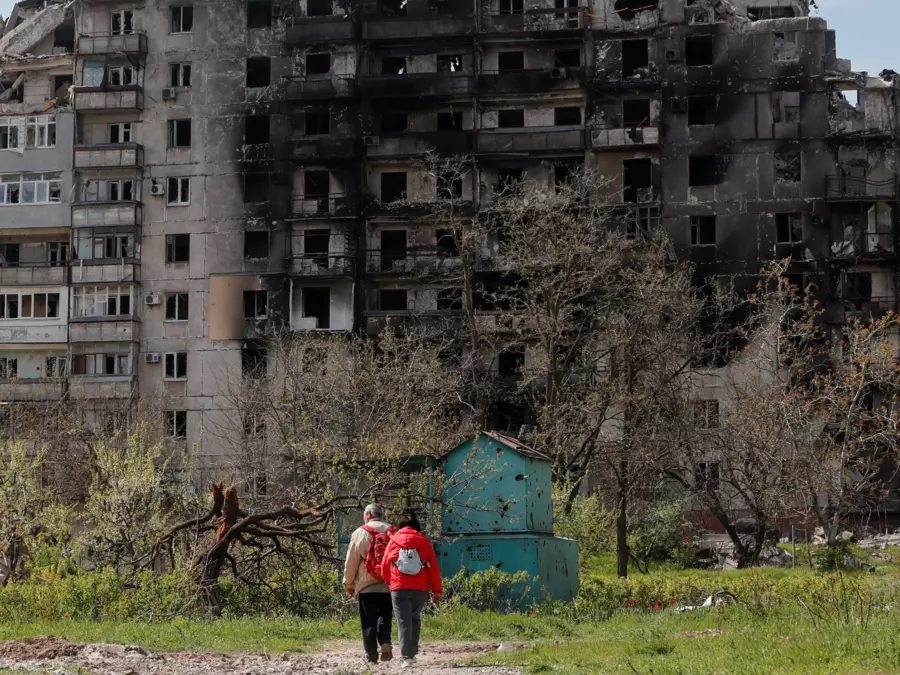 Two people stand outside of a bombed out building in Mariupol, Ukraine