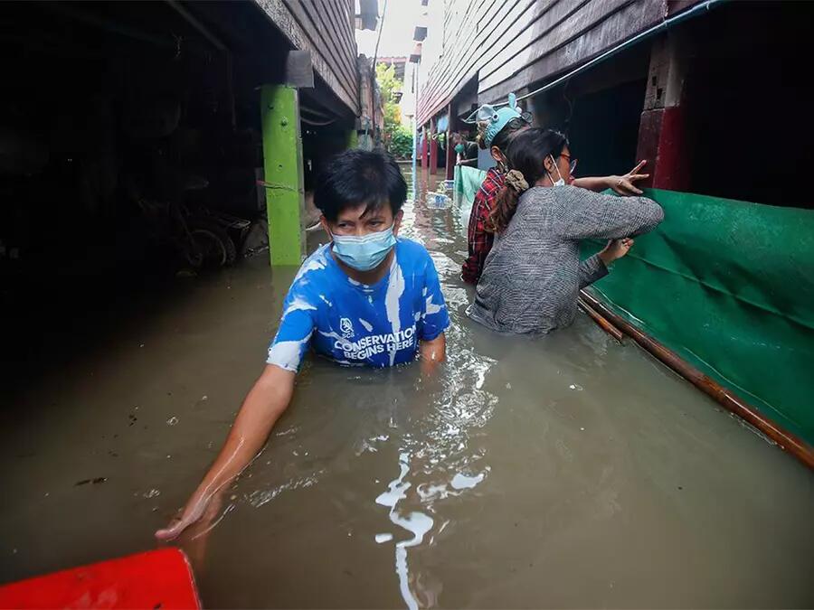 A Thai man navigates near chest deep water in a flooded street