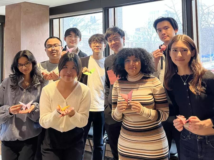 Group of students holding origami smiling at the camera. 