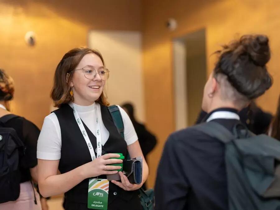 Amalie Wilkinson, Munk One alumnus, speaks to a colleague at COP28 in December, 2023. Amalie is pictured wearing an official COP28 lanyard.