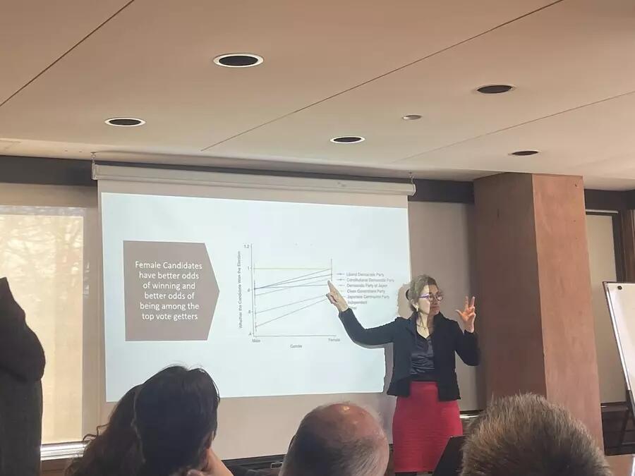 Woman pointing to powerpoint presentation with a graph on it. 