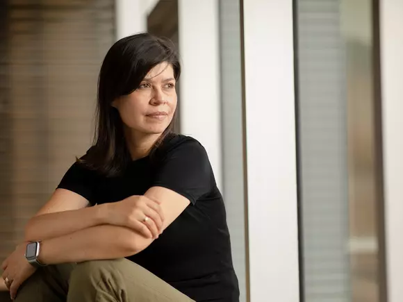 Picture of Martha Balaguera sitting by a window wearing black shirt. 