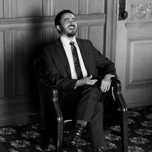 Black and white picture of Robert Gillezeau sitting in a chair and wearing a suit.  