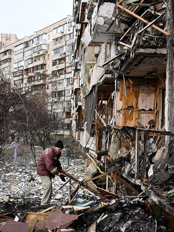 Man looking through rubble after building has been hit by a bomb in a large building complex in Ukraine