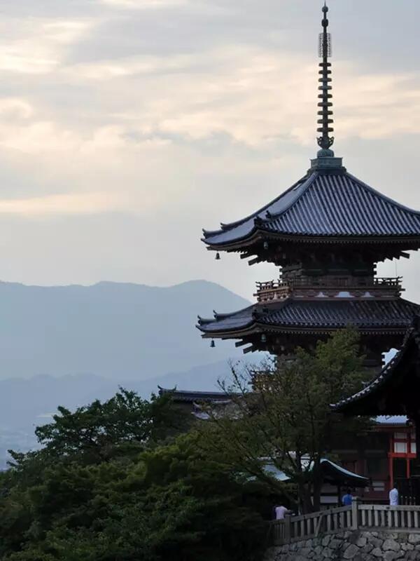 Photo of a Japanese temple with mountains and grey sky in the backgound