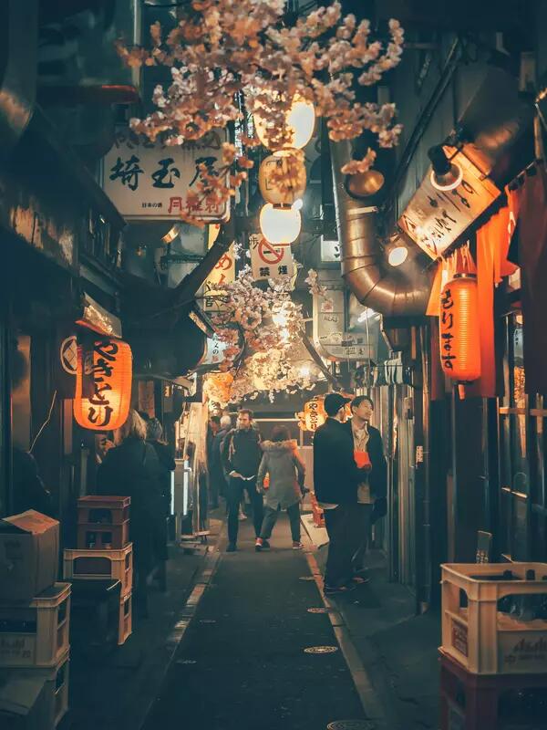 A narrow street in Japan, with red lanterns hanging from storefronts.