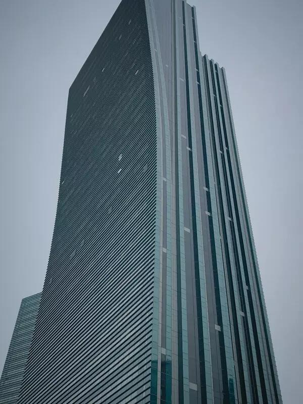 A tall, modern looking tower building in Nur-Sultan, Kazakhstan against a grey sky.