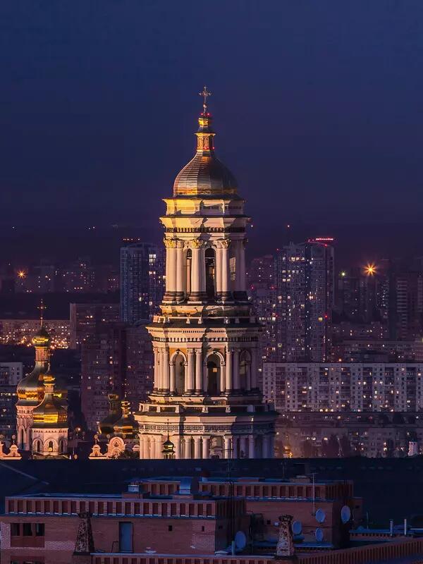 Night shot of Kyiv's skyline, a tall tower in the foreground.