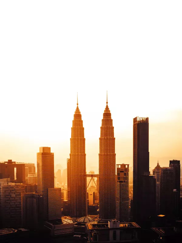 The Petronas Twin Towers in Kuala Lumpur City Centre against an orange sunset.