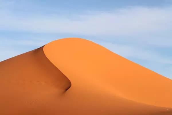 A smooth sand dune against a blue sky