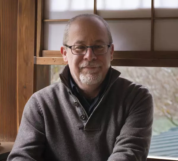 Rick Halpern sitting in front of a window wearing glasses and a grey sweater.